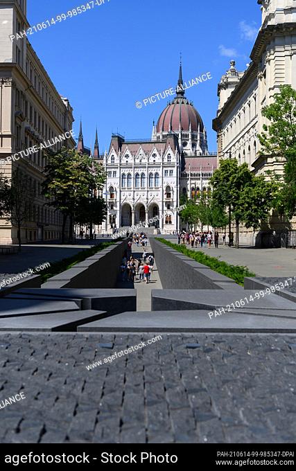 14 June 2021, Hungary, Budapest: Tourists walk out of the National Unity Monument, the Trianon Monument, at Lajos Kossuth Square in front of the Parliament