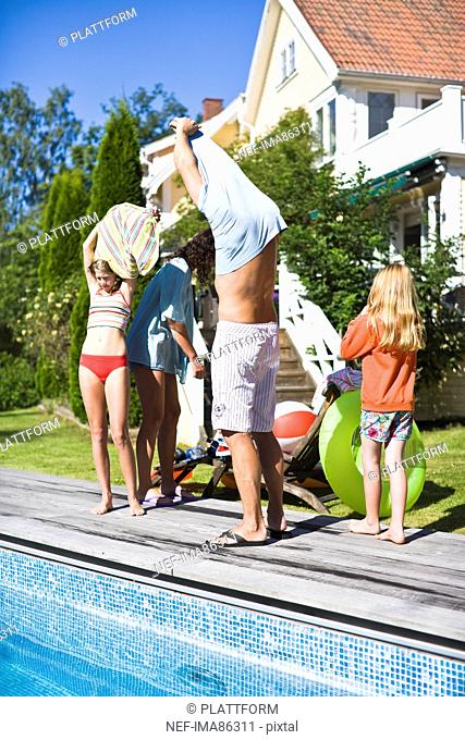 Family taking off cloths near swimming pool
