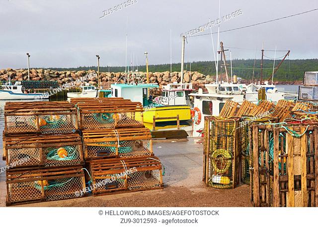 Lobster pots stacked on quay, Neil's Harbour, Victoria County, Cape Breton Island, Nova Scotia, Canada. . A fishing community on the east coast of Cape Breton...