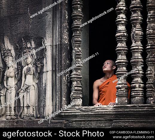 Siem Reap, Cambodia - January 19, 2011: A monk in his orange robe is looking out from the Angkor Wat complex