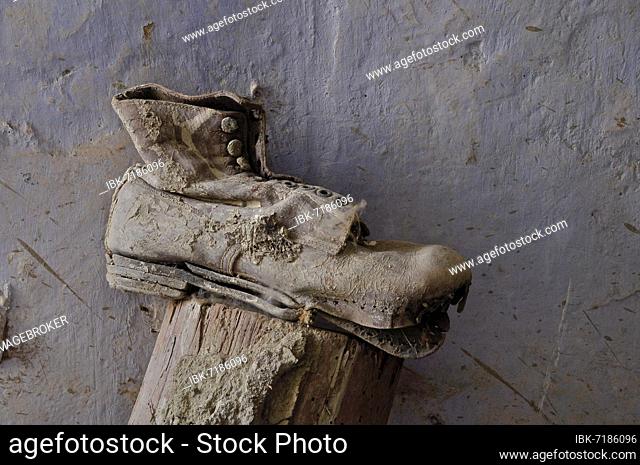 Work shoe with detached sole on wooden trestle in front of grey wall, lace-up boots with earth, Andalusia, Spain, Europe