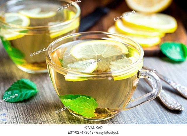 Cup with mint and lemon tea on a wooden table