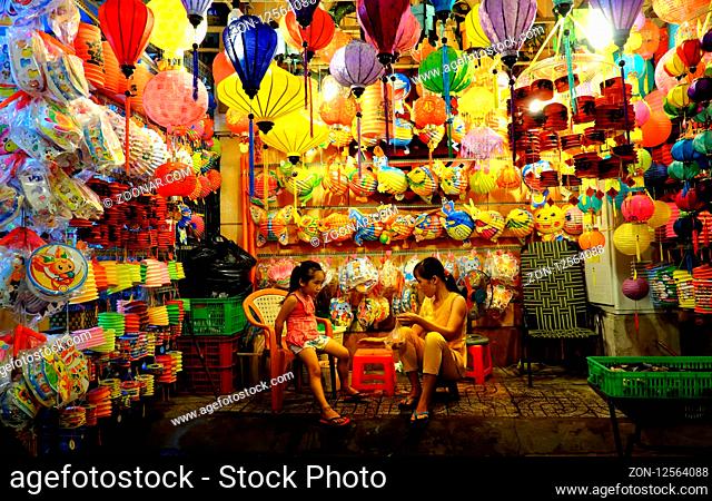 HO CHI MINH CITY, VIET NAM- SEPT 8, 2018: Mother and daughter sit front of colorful lanterns kiosk at lantern street, district 5, Saigon, Vietnam