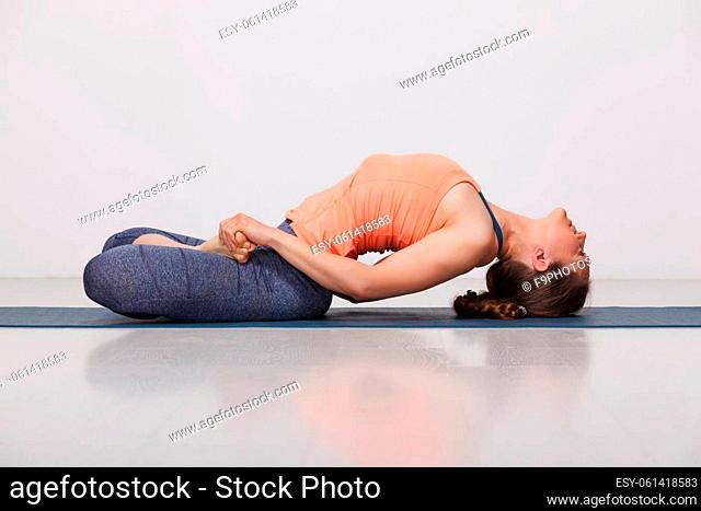 Beautiful sporty fit yogini woman practices yoga asana Matsyasana - fish pose in studio