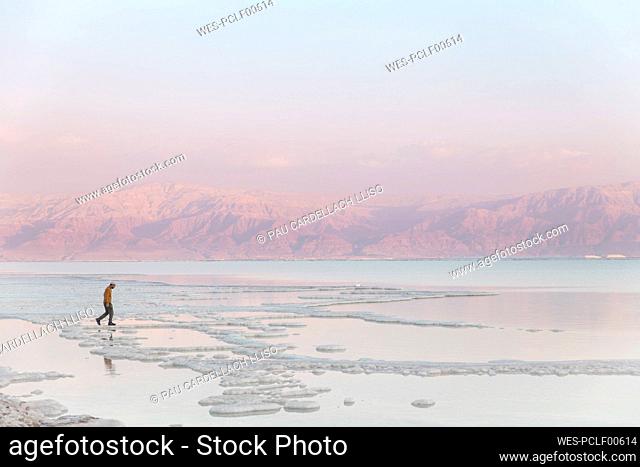 Man walking on salt formations at sunset in dead sea