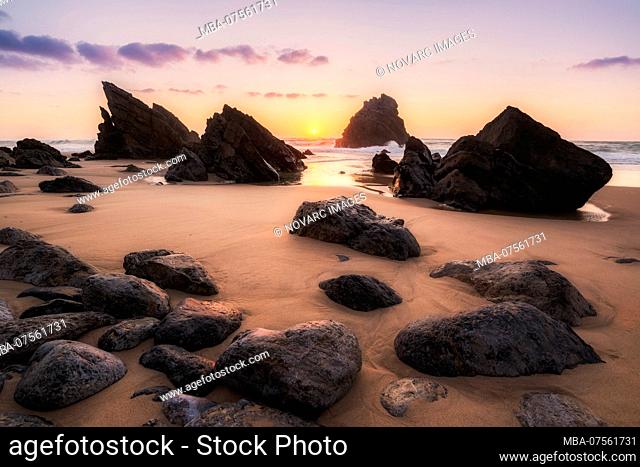 Rocks at low tide on the beach at sunset, Praia da Adraga, Sintra, Portugal
