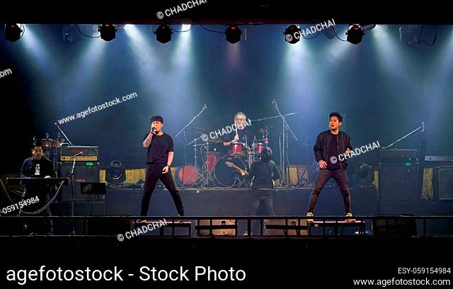 Asian singer, keyboardist, guitarist, drummer, bassist and guitarist of rock band musicians perform in concert on stage for night party