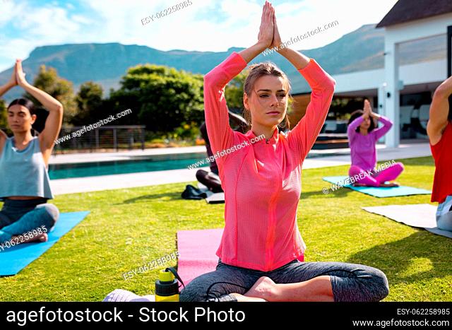 Diverse friends practicing yoga and meditating in garden