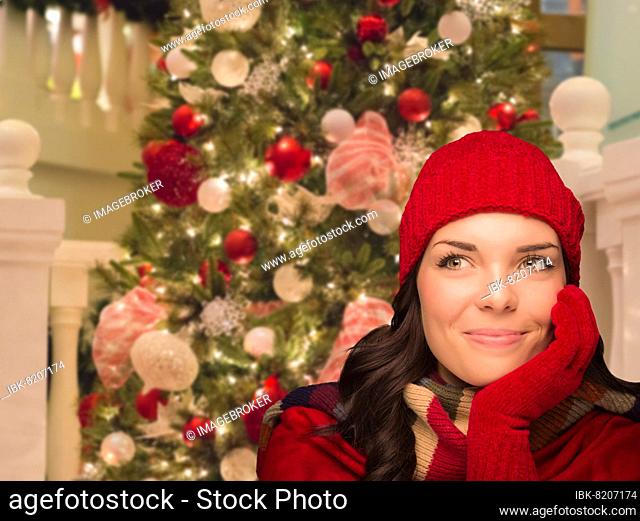 Warmly dressed female in front of decorated christmas tree