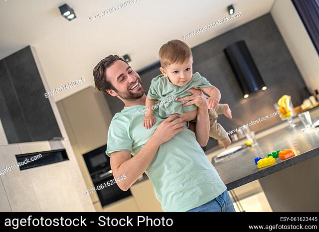 Baby-sitting. Young father spending time with his cute babyboy and looking happy