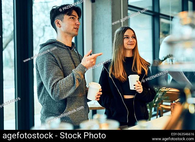Friends doing shopping in a coffee shop. Young man and woman having chat while picking out the pastry, bakery's goods and hot drinks standing at counter in a...