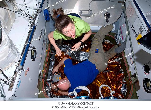 NASA astronauts Scott Kelly, Expedition 26 commander, and Catherine (Cady) Coleman, flight engineer, work in the hatchway of the Harmony node's nadir port of...