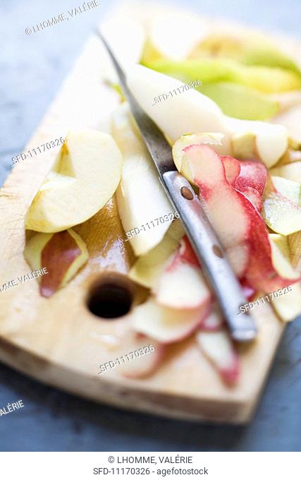 Peeled apples and pears with apple and pear peelings on a wooden board
