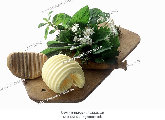 Butter curl on wooden board with herb bouquet