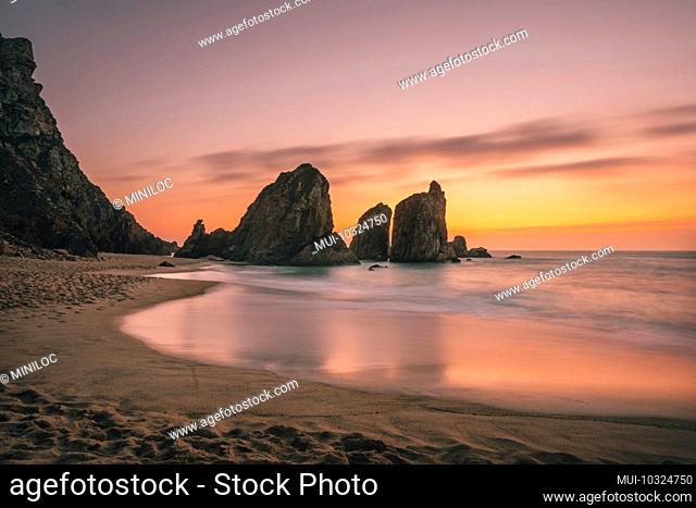Ursa Beach near Cape Roca at Atlantic Ocean coast in Portugal. Sand beach with sea stacks in evening golden sunset sky