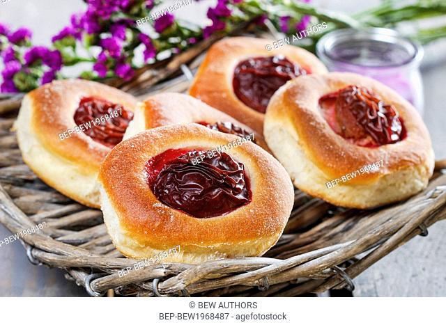 Round buns with plum on wooden table. Party dessert