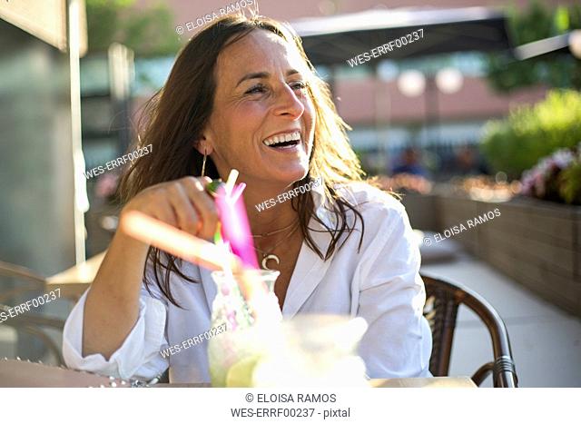 Happy woman sitting in a bar with cocktail glass