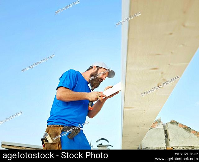 Worker sawing wood with handsaw at construction site