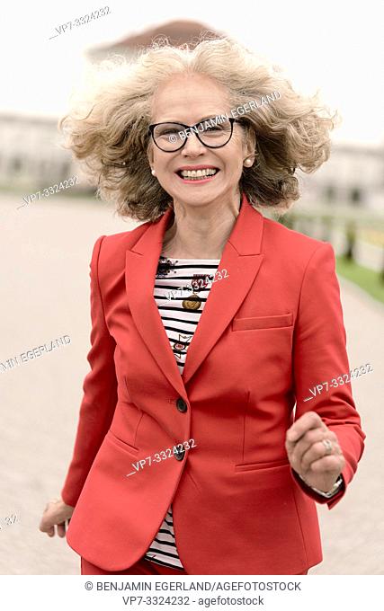 vital senior woman (67 years old) running outdoors in city, in Munich, Germany