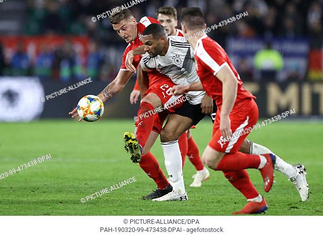 20 March 2019, Lower Saxony, Wolfsburg: Soccer: International match, Germany - Serbia in the Volkswagen Arena. Jonathan Tah (M) from Germany and Sergej...