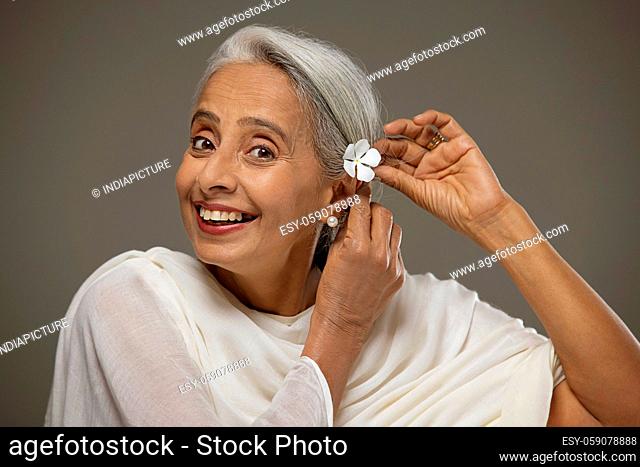 Portrait of old beautiful woman adoring her hair with a flower