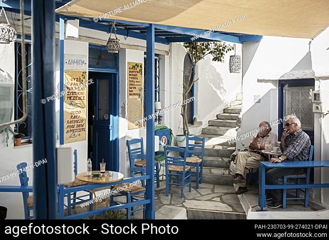 16 June 2023, Greece, Kardiani: Two men sit in a taverna in the main square of the village of Kardiani on the island of Tinos in the Cyclades
