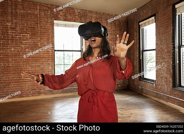 portrait of young ethnic woman wearing VR headset in empty loft