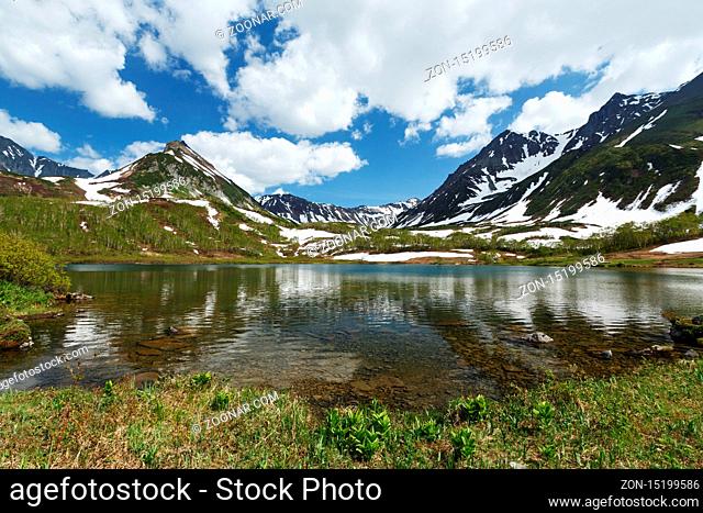 Scenery summer landscape of Kamchatka: beautiful view of Mountain Range Vachkazhets, mountain lake and clouds in blue sky on sunny day