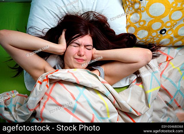 Tired woman sleeping on a bed at home. Noisy neighbors, stress, headache, insomnia concept