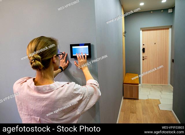 Young woman operating home automation device at home