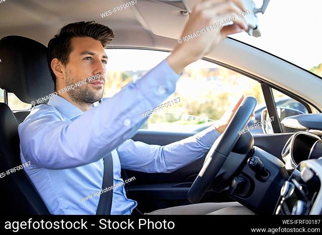 Businessman adjusting rear view mirror while sitting in car