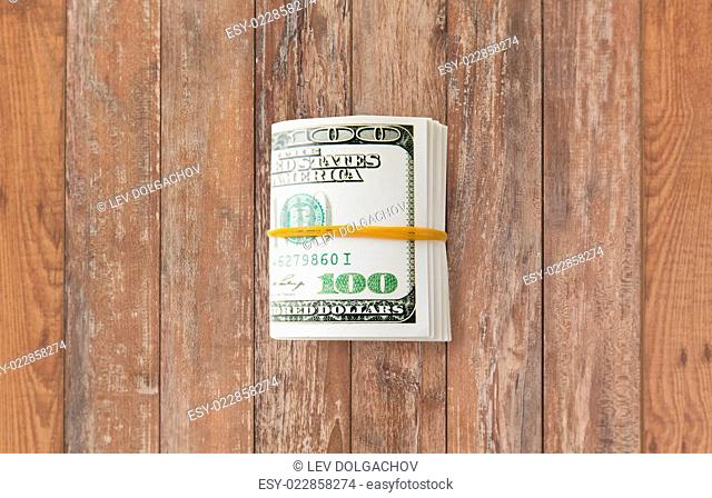 business, finance, investment, saving and corruption concept - close up of dollar money packet tied with rubber on wooden table