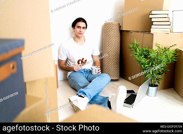 Young man having churro with coffee while sitting at new apartment