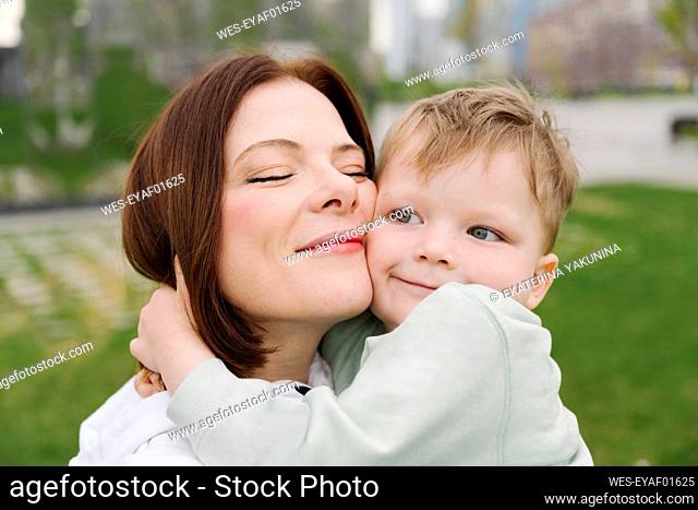 Cute son embracing mother at public park