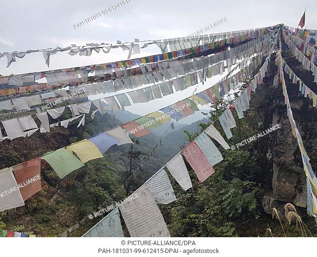 19 October 2018, Bhutan, Wangdue Phodrang: Buddhist prayer flags hanging between rocks in the central Bhutanese Phobjikha valley