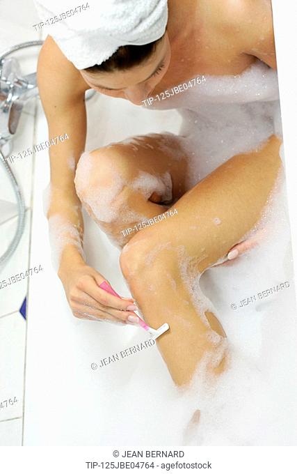Woman having bath and shaving legs