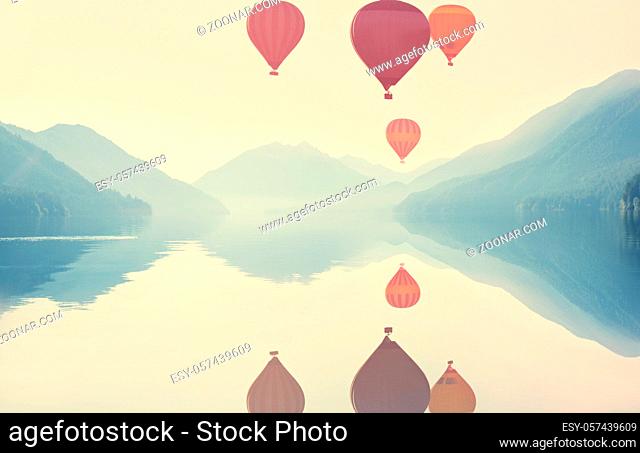 Sunrise over the mountains lake with a air balloons above. Travel background