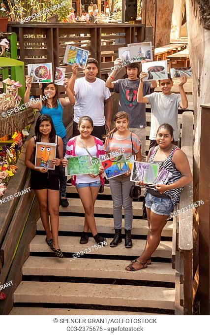 Posing on a staircase, Hispanic middle school art students proudly show off their finished work after a drawing class in Laguna Beach, CA