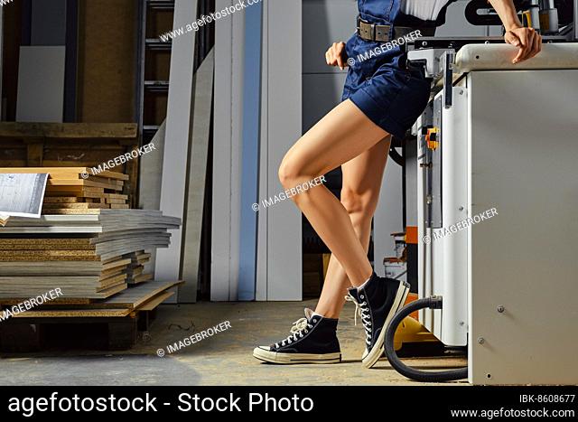 Female legs near a woodworking machine in profile
