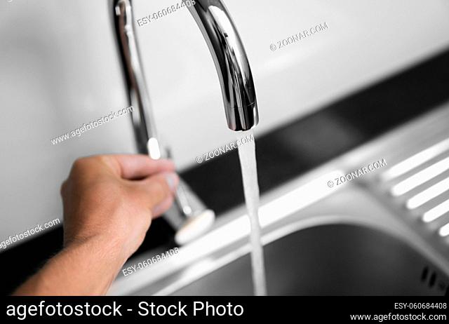 Close up on modern kitchen metal faucet and metal kitchen sink with a running water