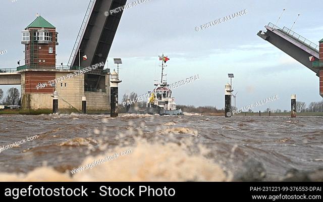 21 December 2023, Lower Saxony, Leer: The tugboat Ems Power crosses the Ems in bad weather and passes the Jann-Berghaus Bridge in the direction of Emden