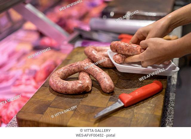 Female butcher cutting sausage