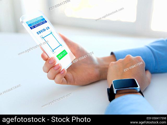 hand with certificate of vaccination on smartphone