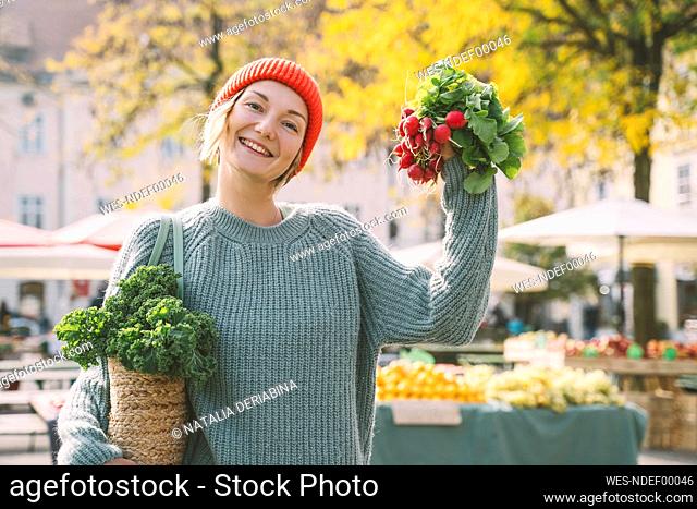 Happy woman holding radish at market