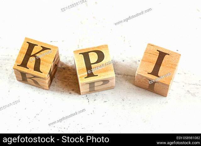 Three wooden cubes with letters KPI stands for Key performance indicator on white board.