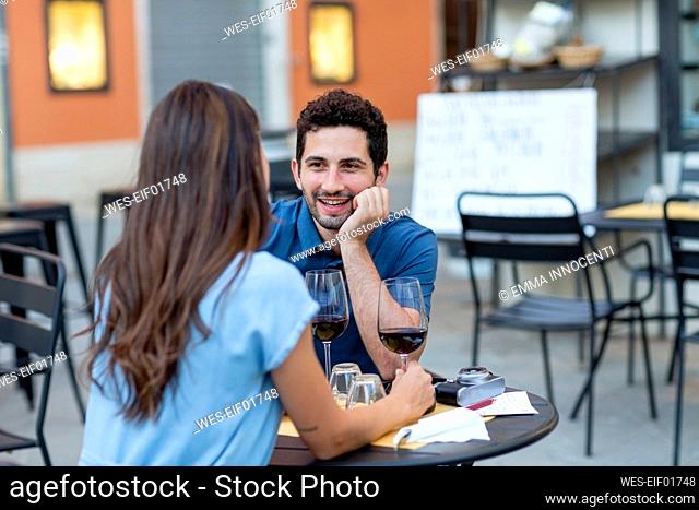 Man with hand on chin talking to girlfriend while sitting at restaurant