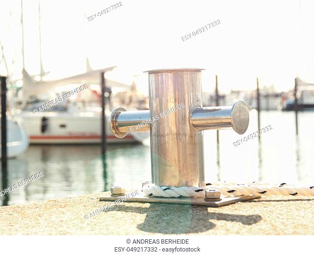 Stainless steel bollard with a rope in a luxury marina
