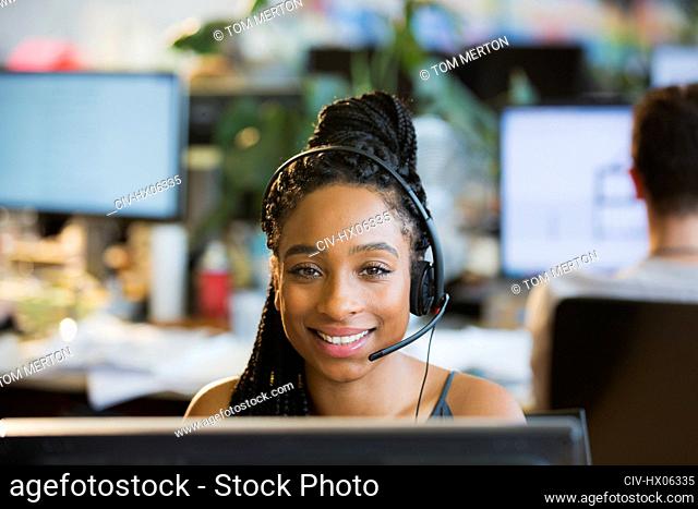 Portrait confident businesswoman with headset at computer in office