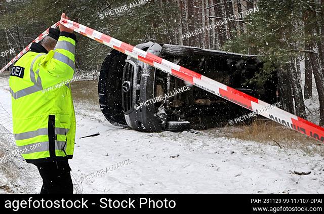 29 November 2023, Mecklenburg-Western Pomerania, Malchow: A van involved in an accident lies next to the A19 highway in the snow-covered forest; the adverse...