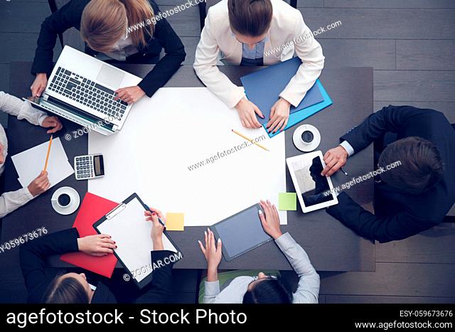 Business workplace with people, coffee, digital tablet, laptop, smartphone, papers and various office objects on table, blank paper with copy space for text